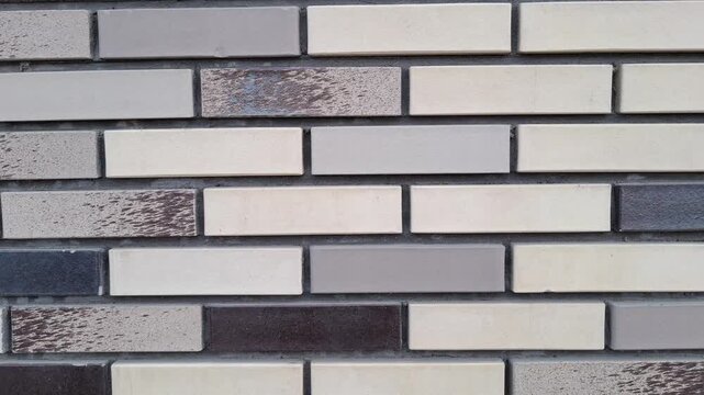 Modern decorative brick wall texture with various shades of grey, beige, and speckled patterns. For architectural backgrounds, construction designs, and contemporary exterior or interior finishes