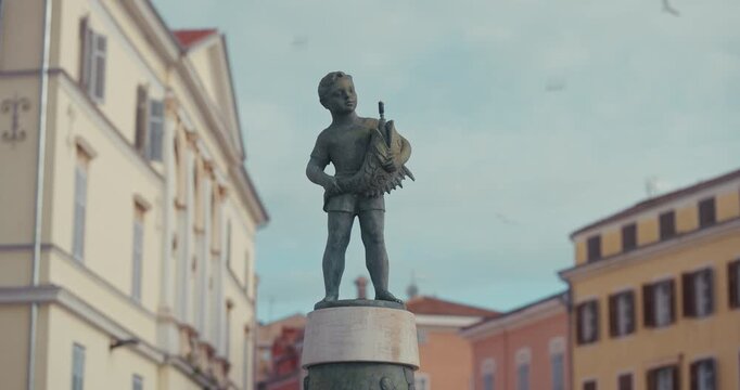 Statue of a boy with a fish on Marshal Tito Square in Rovinj, Istria, Croatia during the morning.