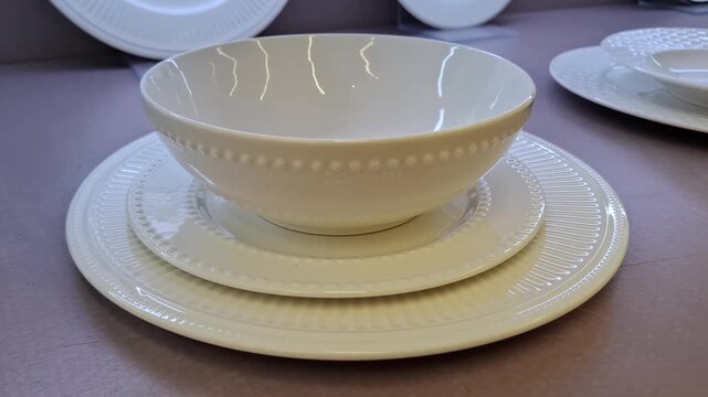 Elegant white ceramic dinnerware set featuring a bowl and matching plates with textured edges. For home decor, fine dining, and kitchen interior. Kitchen items on store shelf