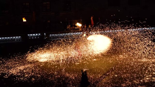 Fire Performer Creating Sparks at Night in City Square