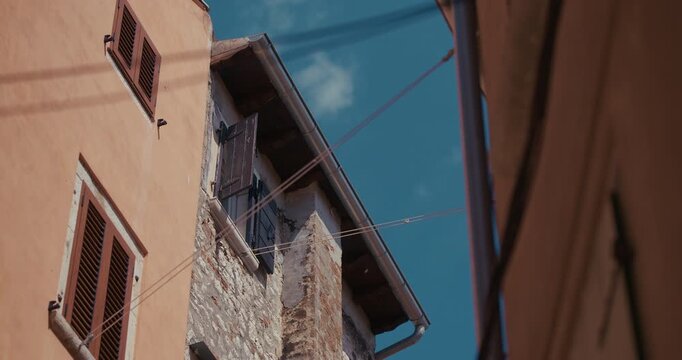 Stone house facade with wooden shutters and overhead clotheslines in the old town of Rovinj, Croatia during the afternoon.