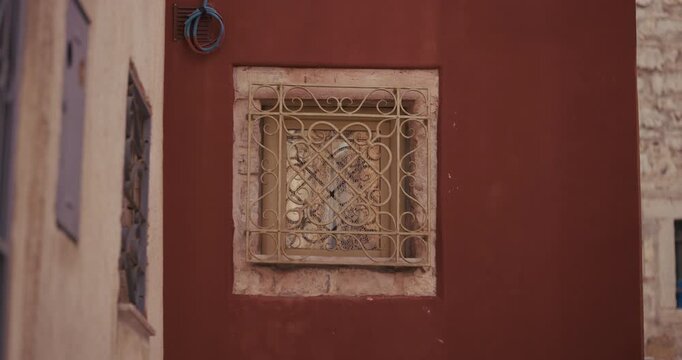Decorative metal window grille on a red facade in the old town of Rovinj, Croatia during the afternoon.