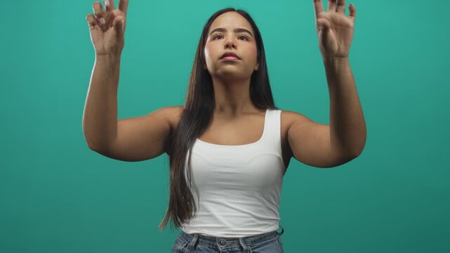 Young woman reaching with bare arms and fingers gesturing upward toward an invisible touchscreen in studio; focus interaction.