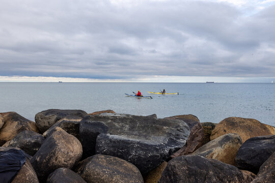 two kayaks on the beach with large rocks in the foreground
