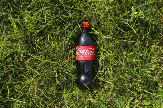 Kyiv, Ukraine - May 6, 2026: Plastic bottle of Coca-Cola Classic drink in green grass, top view. Refreshing Coca-Cola drink on the lawn. Summer picnic, sunny day. Classic 0.5 liter bottle of Coca-Cola