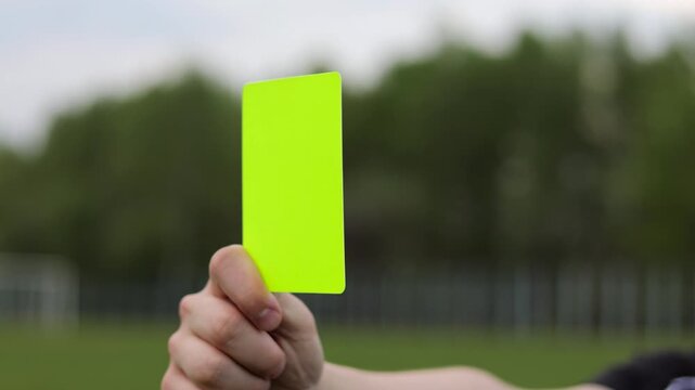 Referee shows yellow card during soccer match at the stadium. Close up