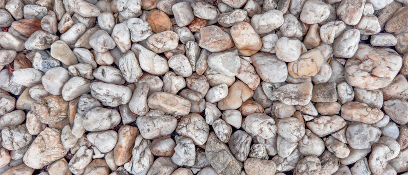 White natural pebbles texture with rounded sea stones and neutral colors, rocky surface background for construction, landscaping, garden decoration and exterior materials.