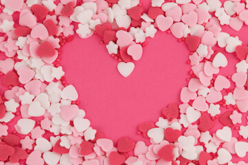 Obraz premium Heart shaped sprinkles forming heart outline on pink