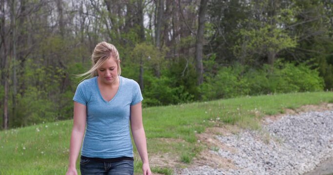 Girl walking by in grass near woods 4k
