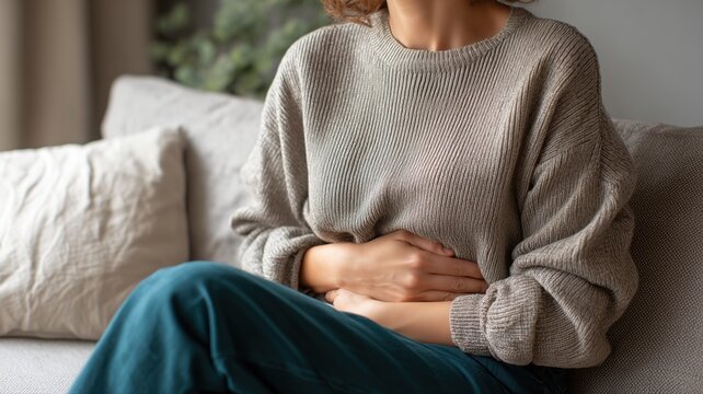 腹部を押さえている女性の上半身。体調不良や生理痛のイメージに使える素材