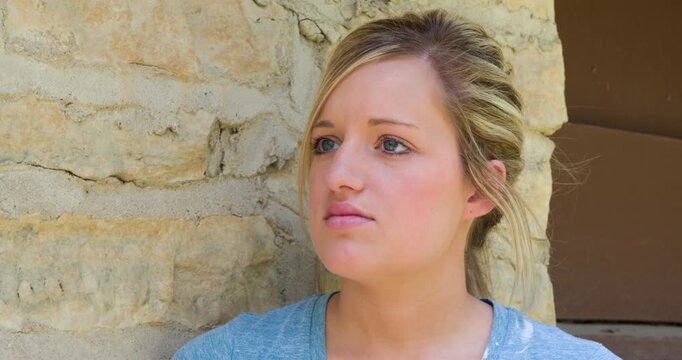Young girl leaning against brick wall 4k
