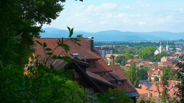 Scenic view of ljubljana slovenia from a high vantage point. High-angle view of ljubljana's traditional red tile roofs and historic architecture, with green trees in the foreground