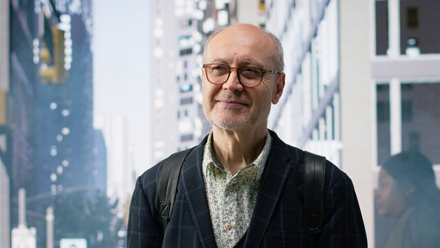 Portrait of senior businessman moving through busy downtown street, multicultural crowd and motion blur capturing realistic city life, commute activity and professional lifestyle. Camera B.