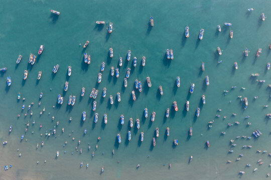Aerial view of Mui Ne Beach with numerous traditional fishing boats and round coracles floating on the turquoise sea Thanh pho Phan Thiet, Binh Thuan, Vietnam.
