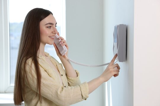 Young woman answering intercom call at home