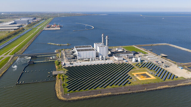 Aerial view of the Maxima Power Plant with solar panel arrays and industrial buildings on the coast of the IJsselmeer in Lelystad, Flevoland, Netherlands.