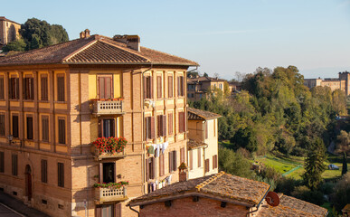 Obraz premium Corner Building with Flower Balconies in Siena Tuscany During Golden Hour with Traditional Italian Urban Architecture
