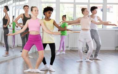 Obraz premium Slim teen boy and girl doing together plie position of ballet during choreography classes