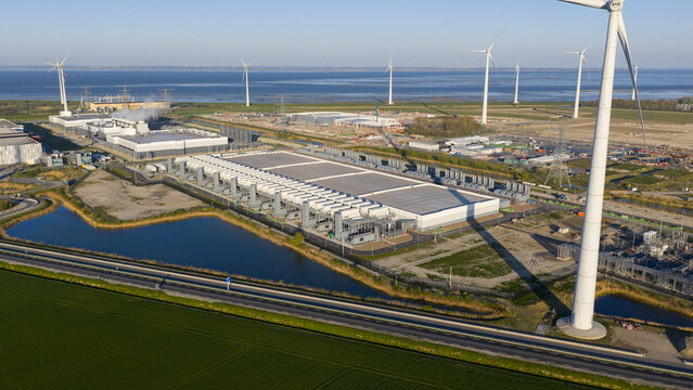 Aerial view of the Google data center complex with wind turbines and industrial infrastructure near the coast in Eemshaven, Groningen, Netherlands.