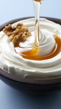 Thick Greek yogurt with walnuts and a drizzle of golden honey in a dark bowl