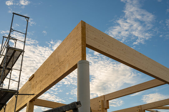 Glulam timber beams joint on concrete column at construction site against blue sky