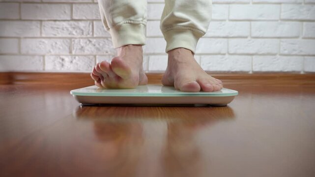Person checking their weight on a digital bathroom scale. Daily ritual of a man stepping on a modern digital bathroom scale to measure his body weight, an essential part of his diet and health routine