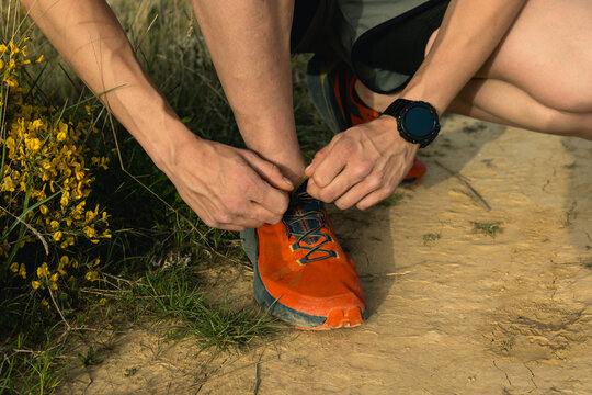 Runner tying shoelace on trail preparing for training run