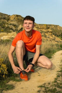 Young man tying shoelace during trail run