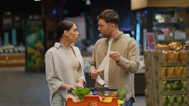 Shocked couple discussing high grocery bill at supermarket