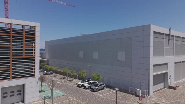 Aerial view of modern office building with wooden louvre facade next to gray warehouse complex and red crane
