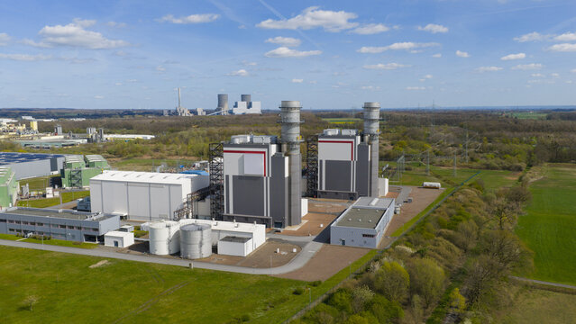 Aerial view of the Trianel Gaskraftwerk Hamm power plant with its modern industrial buildings and tall exhaust stacks surrounded by green fields and forests Hamm, Nordrhein-Westfalen, Germany.
