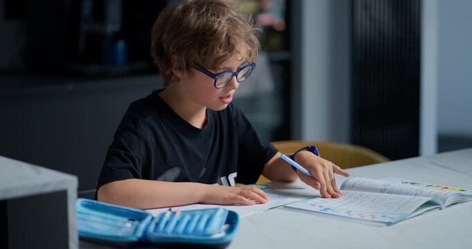 Diligent Young Boy Focuses Intensely While Working Through Educational Exercises At Kitchen Table