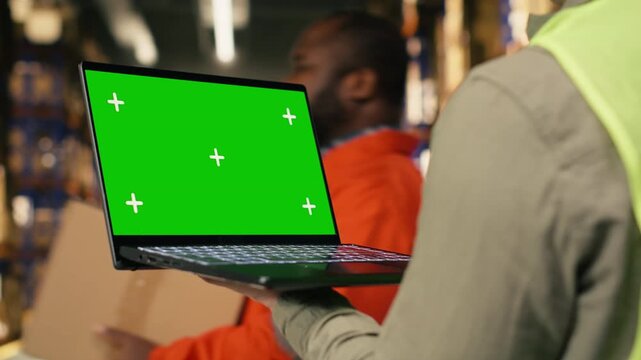 Isolated screen laptop with distribution hub staff near merchandise depot area. Inventory tracking and dispatch activity provide e-commerce operations and manual labor in warehouse.