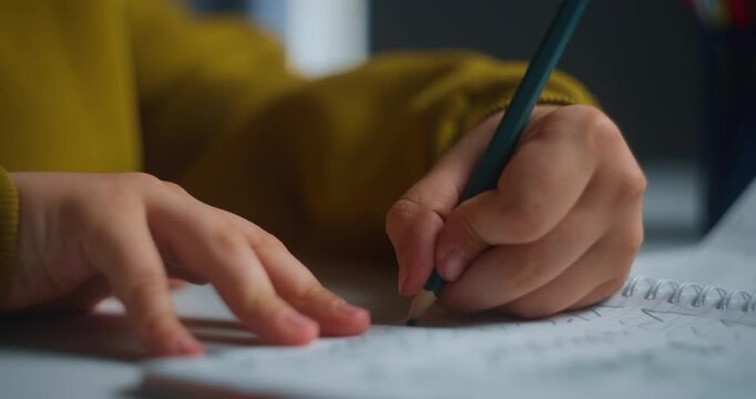 Closeup Of Hands Writing In Notebook. Young Learner Engaged In Handwriting Exercises Under Warm Lighting