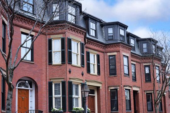 row of old red brick townhouses with bay windows and mansard roof
