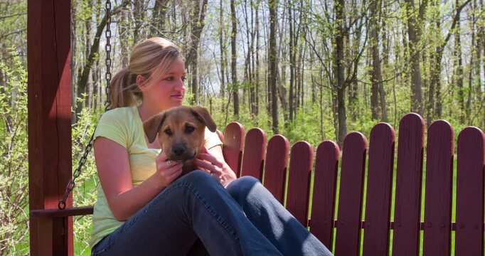 Girl and dog sitting on swinging bench 4k
