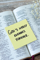 Obraz premium God's mercy endures forever, inspirational quote with holy bible on wooden background. Jesus Christ's grace, compassion, and forgiveness, biblical concept.