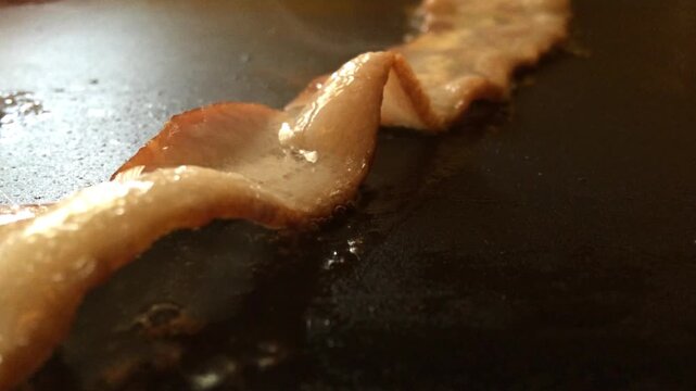 Bacon on griddle sizzling while cooking
