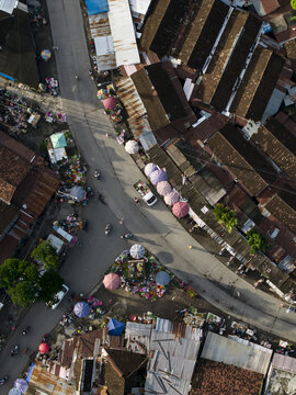 Aerial view of Pasar Kembang Klaten traditional market with colorful umbrellas, busy street intersection, and rustic rooftops Kemalang, Central Java, Indonesia.