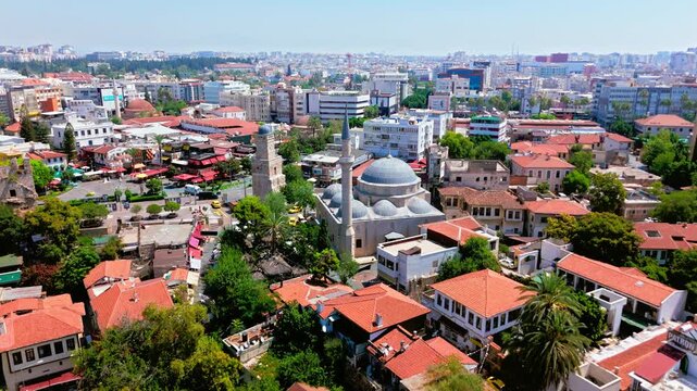 Drone view of Antalya, Turkey Yivli Minare Mosque area. Old town rooftops, green trees and urban skyline create a scenic historic travel view.