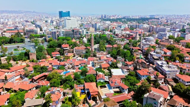 Drone view of Antalya, Turkey Yivli Minare Mosque and Old Town. Red rooftops, green trees and city skyline create a sunny historic travel scene.