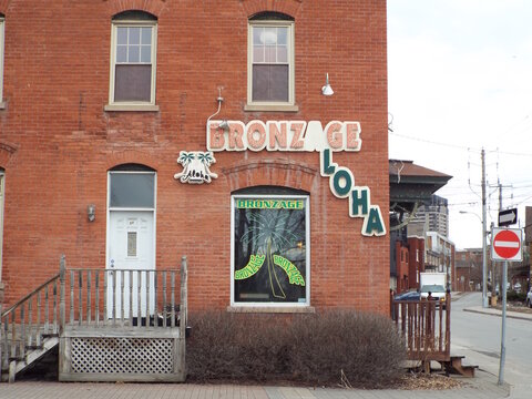 Gatineau, Quebec, Canada &ndash; March 11, 2026: A "Bronzage Aloha" tanning salon, located in a red brick building, features neon window signs and a corner street view at 62 Rue Montcalm.