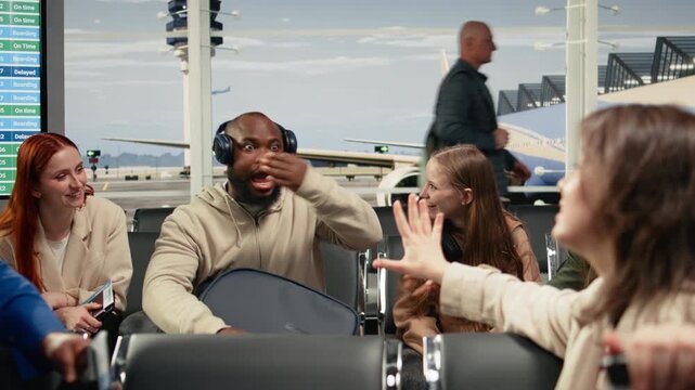 Multiethnic group of friends in airport chatting, waiting for departure gate to open. Travel buddies having fun in air transportation transit hub, preparing for international flight, camera A