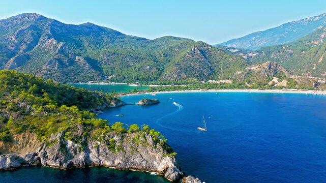 Drone view of Oludeniz Beach, Turkey coast and cliffs. Blue sea, green mountains and rocky shoreline create a peaceful Mediterranean travel scene.