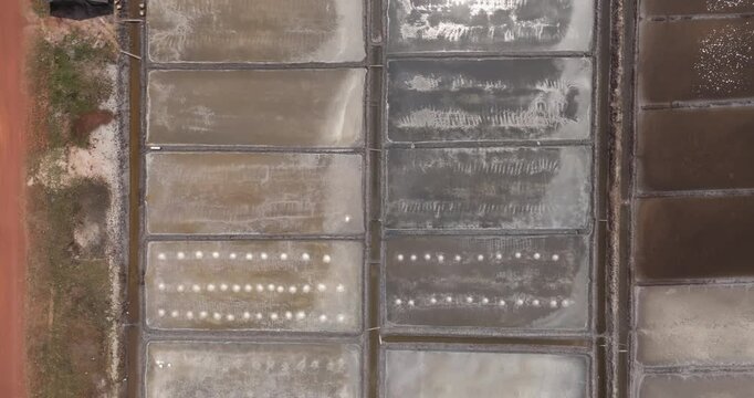 Aerial top down view of rectangular salt evaporation ponds with rows of white mounds