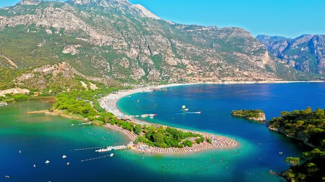 Drone view of Oludeniz Blue Lagoon, Turkey coastline. Sandy beach, blue water and high mountains create a famous summer travel destination.