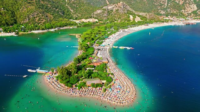 Drone view of Oludeniz Blue Lagoon, Turkey. Curved sandy shore, turquoise water and green peninsula create a scenic summer travel scene.