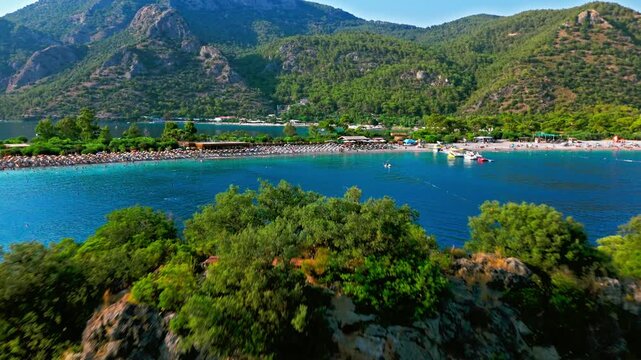 Drone view near Oludeniz Blue Lagoon, Turkey. Blue sea, green cliffs and mountain backdrop create a scenic Mediterranean view.