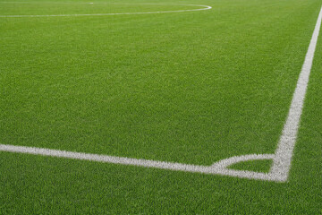 Obraz premium White lines on a green artificial turf soccer field at a sports stadium, corner kick area for football match training and athletic competition background for sports concept