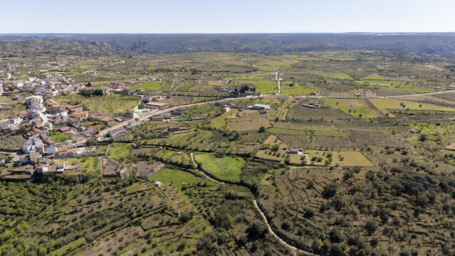 Aerial view of the historic town of Fermoselle nestled among terraced fields, olive groves, and stone walls under a clear sky in Fermoselle, Castile and Leon, Spain.